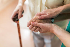 Elderly woman being helped by nursing home nurse.