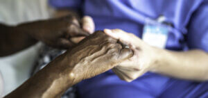 A black patient holds hands with a caregiver after dealing with racial bias