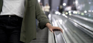 A woman holds the rail of an escalator preventing an escalator accident.