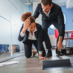 woman slipping and falling in office space, man helping her