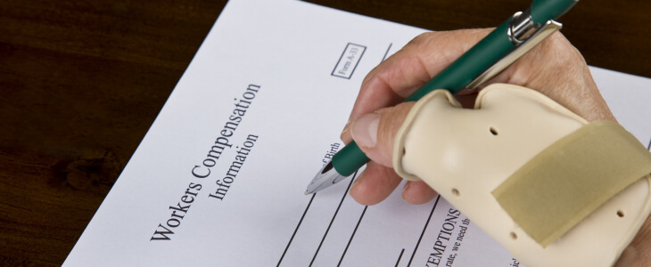 A person with a cast on their hand signs a workers compensation document